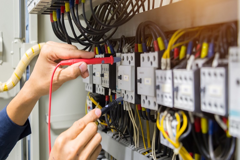 duas mãos masculinas manuseando instrumentos em um quadro de eletricidade